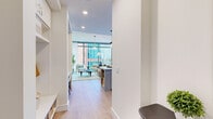 Located in the heart of downtown Austin, TX 78701, this thoughtfully designed one-bedroom, one-bathroom residence offers a sophisticated urban living experience. Light hardwood flooring flows seamlessly throughout, connecting each space with warmth and continuity.

The open-concept living and kitchen area serves as the heart of the home, anchored by dramatic floor-to-ceiling windows that frame sweeping Austin skyline views and flood the interior with abundant natural light. The kitchen features crisp white shaker cabinetry with brass hardware, a white quartz countertop, stainless steel appliances including a gas range, built-in microwave, and refrigerator, all centered around a striking powder-blue island with bar seating and pendant lighting above.

The living room is bright and airy, with expansive glazing offering panoramic city views and pendant and arc lighting adding character. The entrance includes a practical built-in nook, while a hallway leads to the private bedroom. The bedroom is a serene retreat with floor-to-ceiling windows showcasing skyline vistas, a walk-in closet, and warm, neutral finishes.

The bathroom is a true standout, featuring a freestanding soaking tub positioned against full-height glass windows overlooking the Austin cityscape, paired with a sleek double vanity and large-format tile flooring — an exceptional and rare urban sanctuary.