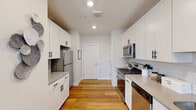 Located at 112 Woodlake Dr in Sayreville, NJ, this well-designed multi-floor residence spans three levels, offering a thoughtfully laid-out living experience with modern finishes throughout. The kitchen features white shaker cabinetry with black hardware, stainless steel appliances including a gas range, microwave, refrigerator, and dishwasher, all complemented by light countertops and warm hardwood flooring that flows seamlessly through the main living areas. The living room is bright and welcoming, lined with multiple windows dressed in bold navy curtains that invite natural light while offering a comfortable, open atmosphere. A staircase with a warm wood handrail connects the floors, adding architectural character to the space. The bedroom is a serene retreat with soft neutral tones, carpet flooring, and windows with blinds and sheer curtains that allow for flexible light control. Bathrooms are finished with subway tile, large-format floor tile, and vanities with stone countertops and black hardware accents. A spacious walk-in closet with wire shelving provides ample storage. The dedicated laundry room houses a full-size front-loading Whirlpool washer and dryer with additional wire shelving for storage, adding everyday convenience to this well-appointed home.