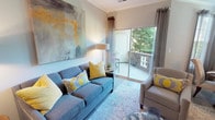 This single-floor, two-bedroom, two-bathroom residence offers a thoughtfully designed layout with a cohesive, contemporary aesthetic throughout. The living room serves as the heart of the home, featuring crown molding, wood-style flooring, and a sliding glass door that opens to a private balcony with outdoor seating and tree-lined views, flooding the space with natural light.

The kitchen is equipped with dark cabinetry, granite countertops, stainless steel appliances, and an electric range, complemented by a window that brings in additional natural light. Adjacent to the kitchen, the dining area accommodates a round table and tufted chairs beneath a large window dressed with sheer curtains and blinds.

Both bedrooms offer carpeted floors and generous natural light. The primary bedroom features a teal accent wall, while the second bedroom includes a walk-in closet. Each bathroom is distinctly appointed — one offers an extended vanity with a wide mirror, wood-style flooring, and ample storage, while the second features a full tub-shower combination. A dedicated in-unit laundry area with a full-size washer and dryer completes this well-rounded residence.