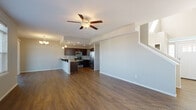Located in Spokane, WA, this two-story residence offers a well-designed layout across two levels, combining modern finishes with functional living spaces throughout. The main level features an open-concept design where the living area flows seamlessly into the kitchen and dining space. Rich hardwood-style flooring anchors the main level, complemented by neutral gray walls and abundant natural light streaming through multiple windows fitted with white blinds. A ceiling fan with integrated lighting serves the living area, while recessed lighting illuminates the kitchen. The kitchen is outfitted with dark espresso cabinetry, granite countertops, a subway tile backsplash, and a full suite of stainless steel appliances including a gas range, microwave, and refrigerator. A raised breakfast bar with decorative corbels and pendant lighting provides additional seating and workspace. A convenient half bath with granite countertops and hardwood-style flooring is also found on the main level. Upstairs, bedrooms feature plush carpeting and natural light. A full bathroom showcases a sliding-glass walk-in shower with tile surround, dark cabinetry, and granite countertops. A dedicated laundry room with upper cabinetry, a utility sink, and washer hookups completes the upper level.