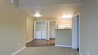 This two-floor residential space offers a practical and well-organized layout designed for comfortable everyday living. The main living area features plush carpeted flooring that transitions into durable hardwood-style flooring in the functional zones beyond, creating a clear distinction between relaxation and utility spaces.

The kitchen is positioned off the main living area and is defined by a peninsula-style breakfast bar that provides both additional counter space and a casual dining option. Light wood cabinetry lines the upper walls, offering ample storage, while white appliances including a built-in microwave add a clean, cohesive look to the space.

A standout feature of this home is the dedicated in-unit laundry area, conveniently tucked behind bi-fold doors and accommodating a full-sized washer and dryer side by side. An additional closet adjacent to the laundry area provides further storage capacity.

The neutral warm-toned walls throughout create a welcoming and versatile backdrop, complemented by flush-mount ceiling lighting that keeps the space feeling bright and open. White trim and baseboards add a crisp, finished detail to each room. Spanning two floors, this space balances functionality and comfort in a well-structured residential layout.