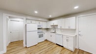 Located at 131 W 200 N in Salt Lake City's Capitol Hill neighborhood, this efficiently designed 3-bedroom, 1-bathroom unit offers a clean, modern aesthetic throughout its single floor. Light-toned luxury vinyl plank flooring runs seamlessly throughout every room, creating a cohesive and low-maintenance foundation.

The open-concept kitchen, dining, and living area serves as the heart of the unit. The kitchen features crisp white shaker-style cabinetry with brushed nickel hardware, white quartz countertops, and a full suite of white appliances including a refrigerator, electric range, built-in microwave, and dishwasher. Recessed lighting illuminates the space, complementing the fresh, neutral color palette.

The living area is open and airy, with recessed lighting and a window that brings in natural light. Each of the three bedrooms offers a quiet, clean retreat with neutral gray walls, recessed lighting, individual wall-mounted AC units, and windows with blinds. The primary bedroom provides a comfortable amount of space for a full furniture arrangement.

The bathroom is fitted with a sliding-door walk-in shower with white tile surround, wood-look flooring, and recessed lighting. A hallway and closet complete the thoughtfully arranged floor plan, maximizing functionality within a compact footprint.