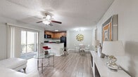 Located in Orlando, FL, this well-designed one-bedroom, one-bathroom unit offers a thoughtful single-floor layout that maximizes every square foot. Light wood-look flooring and neutral tones run throughout, creating a cohesive and airy atmosphere.

The open-concept main area seamlessly connects the kitchen, dining, and living spaces. The kitchen features warm wood cabinetry, dark granite countertops, black appliances including a refrigerator, range, and built-in microwave, and a breakfast bar peninsula with bar seating. Natural light pours in through a sliding glass door that leads to an outdoor area. The dining space accommodates a round glass-top table with modern chrome seating beneath a sputnik-style chandelier. The living room includes a ceiling fan, a sliding patio door, and ample room for comfortable seating.

The bedroom is a calm retreat with a ceiling fan, a window with blinds for natural light, neutral walls, and access to a dedicated closet. The full bathroom features a tub-shower combination with white tile surround, a single vanity, and wood-look flooring. A hallway connects the private spaces efficiently. Textured ceilings are consistent throughout the unit.