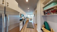Located at 1700 Central Ave in the heart of Saint Petersburg, Florida, this contemporary studio unit offers a thoughtfully designed single-floor layout that maximizes both functionality and style. Warm wood-style flooring runs throughout, creating a cohesive and inviting atmosphere from entry to living area.

The galley-style kitchen is a standout feature, outfitted with a full suite of stainless steel appliances including a refrigerator, electric range, over-the-range microwave, and dishwasher. Crisp white cabinetry extends floor to ceiling, complemented by dark countertops and a subway tile backsplash, offering ample storage and prep space. A built-in entryway nook with open shelving provides additional organization near the front door.

The open living and sleeping area flows seamlessly from the kitchen, allowing for flexible furniture arrangements. Large windows and a glass-panel balcony door fill the space with natural light while offering views of the surrounding neighborhood. The private balcony further extends the living space outdoors.

The bathroom features a tub-shower combination with full tile surround, a vanity with dark countertops, and wood-style flooring that ties into the rest of the unit. Recessed lighting throughout enhances the clean, modern aesthetic of this well-appointed Saint Petersburg residence.