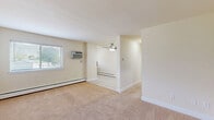 Located at 17 W Vine St in Stowe, PA, this single-floor, two-bedroom, one-bathroom residence offers a practical and comfortable layout. The living room is carpeted in warm neutral tones and features a ceiling fan, baseboard heating, and a window that allows natural light to fill the space. An entry door with a secure deadbolt leads directly into this inviting area, which connects seamlessly to the kitchen and the rest of the unit. The kitchen features tile flooring and cabinetry, providing a functional cooking space. Both bedrooms are carpeted and share a similar light, neutral palette. The primary bedroom is generously sized and features a mirrored sliding-door closet, a window with natural light, and a baseboard heater. The second bedroom also includes a mirrored closet, a window, and a wall-mounted air conditioning unit for individual climate control. The full bathroom is finished with large-format beige tile surrounding a soaking bathtub, offering a clean and classic aesthetic. Baseboard heating is present throughout the unit, and each bedroom is equipped with its own window A/C unit. The overall design is clean and understated, with light-toned walls and carpeting creating a cohesive, move-in-ready atmosphere.
