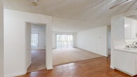 This single-floor unit offers a clean, functional layout designed to maximize comfort and usability throughout. The main living area is spacious and open, featuring warm hardwood flooring that transitions seamlessly into plush carpeting in the adjoining sitting or dining space. Large sliding glass doors fitted with vertical blinds fill the living area with abundant natural light and provide direct access to the outdoors. A ceiling fan overhead adds both style and practicality to the space.

The galley-style kitchen is efficiently designed with crisp white cabinetry, white countertops, and hardwood flooring. It is equipped with stainless steel appliances including a microwave, electric range, and dishwasher, all illuminated by overhead track lighting.

The bedrooms are generously proportioned, each featuring soft wall-to-wall carpeting, white walls, and windows with vertical blinds that allow for natural light and privacy. The textured ceilings carry throughout the sleeping areas, adding a consistent aesthetic touch.

Both bathrooms share a clean, contemporary style, with elongated white vanities, undermount sinks, brushed nickel hardware, and warm hardwood flooring. One bathroom includes a tub-shower combination with sliding glass doors. The overall ambiance throughout the unit is light, neutral, and move-in ready.