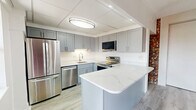 Located at 42 Wyoming St in Pittsburgh's South Side neighborhood (15211), this three-bedroom, one-bathroom unit offers a well-organized single-floor layout with a compelling mix of classic character and modern updates. The living room serves as the heart of the space, showcasing a striking exposed brick fireplace that reaches from floor to ceiling, complemented by built-in shelving, light hardwood-style flooring, and multiple windows that fill the room with natural light and neighborhood views. An accent brick wall in the adjoining area reinforces the space's urban character. The kitchen has been thoughtfully updated with gray shaker cabinetry, stainless steel appliances including a full-size refrigerator, range, microwave, and dishwasher, as well as a marble-style quartz peninsula ideal for dining or prep work. The three bedrooms feature soft carpeting, ceiling fans, and natural light from windows with neighborhood views; the primary bedroom includes an adjacent closet. The full bathroom offers tile flooring, a vanity with storage, a soaking tub, and a glass block window for privacy with diffused light. A dedicated in-unit laundry room houses a full-size washer and dryer. Light hardwood-style flooring flows throughout the common areas, tying the space together cohesively.