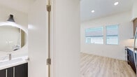 This two-floor studio in Chula Vista, California, offers a thoughtfully designed layout spread across two levels. Light wood-style flooring flows throughout both floors, creating a clean and cohesive aesthetic complemented by bright white walls and recessed lighting.

The main level houses a generously sized open area that serves as the primary living space, featuring soaring ceilings that enhance the sense of openness. Two kitchen areas are present — a standout feature of this unit. The main kitchen is fully equipped with stainless steel appliances, including a refrigerator, dishwasher, and range, paired with navy blue lower cabinetry, wood-tone upper cabinets, and white countertops. An adjacent area provides additional cabinetry and counter space, and the in-unit washer and dryer are conveniently integrated into this zone.

The bathroom is finished with a walk-in shower featuring built-in shelving, matte black fixtures, open wood shelving for storage, and light flooring that maintains the unit's clean palette.

The upper level provides an intimate secondary space bathed in natural light from multiple windows with blinds, and is equipped with a wall-mounted mini-split system for personalized climate control. A loft-style ladder connects the two floors, adding a distinctive architectural element to the studio's efficient and modern design.
