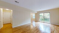 This well-maintained single-floor residence offers a clean, cohesive design highlighted by warm-toned hardwood flooring that flows throughout the main living areas and bedrooms. The open living and dining layout is bathed in natural light, thanks to large sliding glass doors that lead to a private balcony overlooking lush greenery — an inviting extension of the interior living space. A chandelier-lit dining area connects seamlessly to the living room, creating an ideal space for entertaining or everyday living.

The galley-style kitchen is efficiently designed with rich cherry wood cabinetry, granite countertops, a tile backsplash, and a full suite of stainless steel appliances, including a gas range, refrigerator, and dishwasher. Tile flooring in the kitchen provides a practical contrast to the hardwood found elsewhere in the home.

The bedrooms are generously sized, each featuring the same warm hardwood floors, ample closet space, and neutral cream-toned walls that lend a calm, versatile backdrop. One bedroom includes a built-in closet system, while another offers direct access to additional storage.

The bathroom is finished with large-format white tile flooring, a rich cherry wood vanity topped with granite, and a glass-enclosed shower, offering a clean and functional design. A hallway connects all rooms, providing a logical and comfortable flow throughout the entire space.