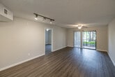Located at 2277 Arbour Walk Cir in Naples, FL, this 2-bedroom, 2-bathroom single-story home offers a well-designed, efficient layout with a clean, neutral aesthetic throughout. Wood-look flooring flows seamlessly across the main living areas, complementing the bright, airy feel created by large windows dressed with vertical blinds that invite natural light.

The open-plan living and dining area provides a generous, versatile space anchored by ceiling fans and track lighting. It connects directly to the kitchen, which features white shaker-style cabinetry, stone-look countertops, a peninsula with additional workspace, and black appliances — an efficient and attractive setup for everyday use.

Both bedrooms are comfortably sized, each with neutral walls, wood-look flooring, and ample closet storage — with three closets distributed throughout the home. The primary bedroom benefits from a large window with outdoor views of surrounding greenery. The two bathrooms are finished with white tile tub-and-shower combos, stone-look vanity countertops, white cabinetry, and chrome fixtures, maintaining a consistent, clean design language.

A dedicated laundry room houses a full-size Whirlpool washer and dryer with overhead shelving. The home also includes a utility room, hallway, and additional unclassified space. Textured ceilings are present throughout, adding a classic Florida residential character to the home.