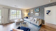 Located at One Avalon Drive in Peabody, Massachusetts, this well-appointed 2-bedroom, 2-bathroom residence offers a thoughtfully designed single-floor layout that balances comfort and style. Warm hardwood-style flooring flows consistently throughout the home, creating a cohesive and inviting atmosphere.

The living room serves as a central gathering space, highlighted by a striking exposed brick accent wall that adds texture and character. Large windows invite an abundance of natural light and provide pleasant views of the surrounding greenery.

The kitchen is outfitted with crisp white shaker cabinetry, stone countertops, a classic subway tile backsplash, and stainless steel appliances — offering both functionality and clean, modern aesthetics. Adjacent to the kitchen, the bright dining area is surrounded by oversized windows framing peaceful outdoor views of mature trees and landscaping, making it an ideal spot for everyday meals or entertaining.

The primary bedroom is generously sized, featuring large windows with garden views and easy access to a dedicated bathroom. The second bedroom is equally comfortable and well-lit. Both bathrooms are finished with clean, classic tile work, including a tiled tub-shower combination. A private balcony accessible from the unit rounds out this residence with a serene outdoor retreat overlooking lush, landscaped grounds.