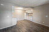 Located at 302 W G St in Ontario, California, this single-story residence offers a practical and functional layout across several well-defined living spaces. The open-concept kitchen and living area serves as the heart of the unit, featuring light wood-look vinyl flooring that extends throughout the common areas. The kitchen is equipped with white cabinetry, a double sink, a white range, and a refrigerator, all set beneath a recessed ceiling detail with built-in lighting that adds definition to the space. A peninsula-style counter provides additional workspace and visual separation between the kitchen and the adjoining living area. Multiple bedrooms are finished with wall-to-wall carpet in neutral tones, offering a comfortable feel underfoot. Each bedroom benefits from natural light through windows overlooking outdoor greenery. One entry area features durable wood-look flooring and a wall-mounted air conditioning unit for climate control. The bathroom is appointed with a wide granite-style countertop, white cabinetry with ample drawer storage, a large wall mirror, and a shower-tub combination. Textured ceilings are consistent throughout the unit, and neutral wall tones create a clean, cohesive aesthetic that complements a variety of interior styles.