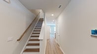 Located on Hawthorne View Ct in Fuquay-Varina, NC, this well-appointed two-story home combines modern design with functional living spaces. Light hardwood-style flooring flows consistently throughout the main level, creating a cohesive and clean aesthetic. The open-concept kitchen is a standout feature, showcasing white shaker cabinetry, a center island with an integrated sink and light countertops, and stainless steel appliances including a refrigerator, range, and microwave. Recessed lighting illuminates the space, which connects seamlessly to the adjacent living area. A convenient half bath on the main level features a pedestal sink and a framed mirror with chrome fixtures. The attached garage offers generous space and is equipped with an automatic door opener. A staircase with dark wood treads and white risers, accented by a wooden handrail, leads to the upper level. Upstairs, the primary bedroom features vaulted ceilings and a ceiling fan, while additional bedrooms are bright and well-sized, each with large windows that bring in natural light and views of the surrounding greenery. A full bathroom upstairs includes a single-sink vanity with white cabinetry, a tub-shower combo, and tile flooring. Throughout, the home maintains a clean, neutral palette ideal for a variety of interior styles.