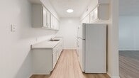 This well-organized single-floor residence offers a practical and comfortable layout across its one bedroom and one bathroom. The open-concept living room serves as the heart of the unit, featuring light wood-style flooring, neutral white walls, and a textured ceiling that adds subtle dimension. A large window dressed with vertical blinds allows natural light to fill the space, creating a bright and airy atmosphere. The front entry opens directly into this generous living area, offering a clean and welcoming first impression.

The galley-style kitchen runs along one side of the unit and is efficiently appointed with white cabinetry — both upper and lower — providing ample storage. Light countertops, a single-basin sink, and white appliances including a full-size refrigerator and range complete the functional cooking space. A recessed ceiling light ensures the kitchen is well-lit.

The bedroom is a comfortable, carpeted retreat with soft neutral tones and a window with vertical blinds that brings in natural light. A dedicated closet provides organized storage. Two hallways connect the living areas to the private spaces, contributing to a logical flow throughout.

The bathroom includes a full-size soaking tub with a shower, surrounded by a clean white surround with built-in shelving, paired with chrome fixtures and a toilet — all finished in a simple, cohesive style.