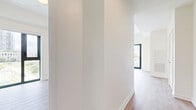 Located at 25 Gibbs Road in Toronto's Etobicoke neighbourhood, this contemporary 2-bedroom, 2-bathroom unit offers a thoughtfully designed open-concept layout finished with clean, modern details throughout. Light-toned hardwood flooring flows seamlessly across the main living areas, complementing the bright, neutral palette of the walls and trim.

The open living and kitchen area is a standout feature, anchored by a sleek, modern kitchen equipped with stainless steel appliances — including a full-size refrigerator, range, and built-in microwave — white cabinetry extending to the ceiling, and a white tile backsplash. Floor-to-ceiling windows flood the space with natural light and frame views of the surrounding Toronto skyline.

The primary bedroom features sliding glass door access to a private balcony with glass railings, offering open city views. The second bedroom is bright and well-proportioned with its own large window and mirrored closet. Both rooms feature the same light hardwood flooring consistent with the rest of the unit.

The two bathrooms are finished to a modern standard. The main bathroom includes a soaker tub with full-height beige tile surround and chrome fixtures, while the ensuite features a sleek white vanity with integrated sink, backlit medicine cabinet mirror, and large-format grey floor tiles. A welcoming hallway connects all areas of the unit efficiently.