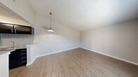 Located at 409 East William Cannon Drive in Austin, Texas, this one-bedroom, one-bathroom unit offers a practical and well-appointed layout across a single floor. Wood-look flooring runs throughout, lending a clean, cohesive feel to the entire space.

The combined kitchen and living area serves as the heart of the unit. The kitchen is outfitted with dark espresso cabinetry, light granite countertops, a gray subway tile backsplash, and black appliances, including a full-size refrigerator. A stylish pendant light fixture hangs above the kitchen peninsula, adding a modern accent to the space.

The living area features a ceiling fan and a sliding glass door that opens to a private balcony, allowing natural light to filter in and providing outdoor views of the surrounding neighborhood.

The bedroom is a comfortable size, featuring mirrored sliding closet doors, a ceiling fan, and a large window fitted with horizontal blinds that allow for ample natural light and privacy control.

The bathroom is finished with large-format, neutral gray tile surrounding a full soaking tub and shower combination, complemented by classic chrome fixtures.

Throughout the unit, textured ceilings and neutral wall tones create a bright, clean atmosphere that is both functional and inviting.