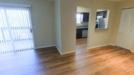 This single-floor residence offers a clean, open layout that promotes a comfortable and functional living environment. The main living area is finished with rich, warm-toned hardwood floors that run throughout, adding character and a sense of continuity to the space. Neutral-toned walls provide a versatile backdrop, complementing a variety of interior styles.

An arched passageway connects the living area to the kitchen, creating a natural flow between the two spaces while maintaining a degree of separation. The kitchen is well-appointed with dark espresso cabinetry, stone-look countertops, and stainless steel appliances including a refrigerator and built-in microwave. A dishwasher is also integrated into the cabinetry, adding convenience. Natural light filters into the kitchen through a window above the sink, brightening the workspace.

A sliding glass door in the living area provides access to an outdoor space, allowing natural light to fill the interior and offering a seamless connection to the exterior. White baseboards and clean wall finishes throughout contribute to a polished, well-maintained aesthetic. Overall, this residence balances practicality with inviting design, making it a functional and comfortable single-level home.