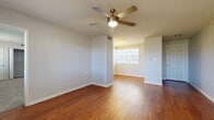 This single-floor, 1-bedroom, 1-bathroom residence offers a practical and comfortable layout across a well-utilized footprint. The living area features rich hardwood flooring that extends throughout the main living spaces, complemented by neutral gray walls and a ceiling fan with integrated lighting. Multiple windows dressed with horizontal blinds allow natural light to fill the room, creating a bright and airy atmosphere. A dedicated entry door adds a welcoming touch to the living space.

The kitchen is outfitted with white cabinetry, granite-style countertops, a tile backsplash, and stainless steel appliances, including a dishwasher. Clean white tile flooring ties the space together, and a stacked washer and dryer unit is conveniently integrated into the kitchen area.

The generously sized primary bedroom is carpeted for comfort and features two large bifold-door closets offering ample storage. A ceiling fan, multiple windows, and a panel door connecting to the rest of the unit complete the room. The bathroom includes a full tub and shower combination with white tile surround accented by a decorative gray tile border.

Overall, the space presents a clean, functional design with consistent finishes and thoughtful details throughout.
