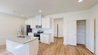 This two-story home in LaGrange, Georgia offers a well-organized layout across two floors, combining functional living spaces with clean, modern finishes throughout. The main level features an open-concept kitchen and living area, where the kitchen stands out with crisp white shaker cabinetry, granite countertops, stainless steel appliances including a refrigerator, electric range, and microwave, and a central island with a built-in sink. Light hardwood-style flooring runs throughout the main living areas, complementing the neutral white walls and recessed lighting. The living room is highlighted by a fireplace with a sleek black surround, a ceiling fan, and windows that bring in natural light. A two-car garage with an automatic opener and a dedicated laundry room with a full-size washer and dryer complete the lower level. Upstairs, three bedrooms are well-proportioned, with the spacious primary bedroom offering a walk-in closet. Three full bathrooms serve the home, each finished with clean, simple fixtures. A dedicated closet and hallways provide additional storage and circulation throughout. The home's consistent use of light tones, hardwood-style flooring, and modern fixtures creates a bright, cohesive atmosphere.