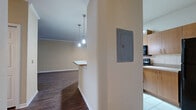 Located at 1930 Devonwood Dr in Wesley Chapel, FL, this two-bedroom, one-bathroom single-floor residence offers a well-organized layout with a variety of thoughtful finishes throughout. The entrance opens to a spacious living room featuring rich dark hardwood flooring, crown molding, and a ceiling fan. Natural light filters in through double windows fitted with blinds, and a glass door provides an outdoor view. A chair rail detail adds a classic architectural touch to the living area.

The kitchen is designed for functionality, featuring warm wood cabinetry, light countertops, white tile flooring, and black appliances including a range, dishwasher, and refrigerator. Track lighting illuminates the galley-style layout, while a peninsula with pendant lighting and a built-in sink connects the kitchen to the living space. A louvered closet door provides additional storage within the kitchen area.

Both bedrooms are carpeted and equipped with ceiling fans. The primary bedroom is generously sized and includes a walk-in closet, while the second bedroom features a window with natural views. The full bathroom includes a tiled tub-shower combination, a vanity with wood cabinetry and a large mirror, and tile flooring. A hallway and dedicated entrance complete the efficient floor plan.