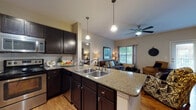 Located at 7902 E Country Dr in Laredo, TX, this single-story residence offers a well-designed, open-concept layout that seamlessly connects the kitchen, dining, and living areas. The kitchen is a standout feature, showcasing rich dark cabinetry, granite countertops, stainless steel appliances including a range, microwave, and refrigerator, and a peninsula with a double stainless steel sink and pendant lighting overhead. Wood-look flooring flows throughout the main living areas, adding warmth and continuity to the space. The living room is bright and inviting, benefiting from natural light through multiple windows with blinds and curtains, and is topped with a ceiling fan for added comfort. A private entry door provides convenient access. The bedroom is a comfortable retreat, featuring carpeted flooring, a ceiling fan, natural light from a window, and access to a spacious walk-in closet. The bathroom is finished with granite countertops on dark cabinetry, wood-look flooring, and a glass-enclosed shower. Throughout the unit, the consistent use of granite surfaces and dark wood cabinetry creates a cohesive, polished aesthetic, making this a functional and attractive single-floor residence.