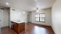 Located at 311 E Hickory St in Denton, TX, this one-bedroom, one-bathroom unit offers a thoughtfully designed single-floor layout that maximizes every square foot. The open-concept living and kitchen area is anchored by a central island with granite countertops and a double sink, illuminated by stylish pendant lighting. Rich hardwood-style flooring extends throughout the main living space, complementing the warm-toned cabinetry. The kitchen is well-equipped with a full suite of stainless steel appliances, including a refrigerator, electric range, and microwave. A ceiling fan with light fixture serves the living area, which benefits from natural light through a window fitted with blinds. The bedroom features soft carpeting, a window for natural light, and access to a dedicated closet. The bathroom is finished with tile-surround tub and shower, a granite-top vanity with undermount sink, matching cabinetry, and hardwood-style flooring. The clean, neutral palette throughout the unit creates a bright and cohesive ambiance, offering a practical and comfortable living environment in the heart of Denton.