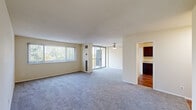 This single-floor residence offers a thoughtfully organized layout encompassing two bedrooms, two bathrooms, a living room, kitchen, and a closet. The living room is a generously sized, open area featuring soft carpeting, neutral wall tones, and abundant natural light supplied by large sliding glass doors that lead to a private balcony with outdoor views of surrounding greenery. A ceiling fan adds to the room's functionality. The kitchen is outfitted with rich dark wood cabinetry, granite-style countertops, hardwood flooring, and black appliances including a gas range and refrigerator, alongside a dedicated pantry closet. The spacious primary bedroom features plush carpeting, a closet, and a window fitted with vertical blinds. The second bedroom similarly offers carpeted flooring and a window for natural light. Both bathrooms are finished with dark wood vanities, granite-style countertops, tile flooring, and tub-shower combinations. Neutral tones and consistent finishes throughout contribute to a cohesive, clean aesthetic across the entire residence.