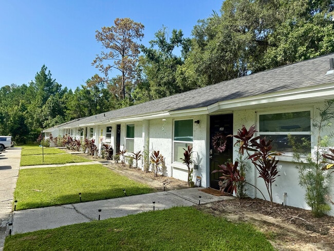 Charming row of single-story homes with lush greenery and modern landscaping in a serene neighborhood setting. - Sunny Creek Apartments