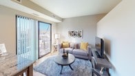 This single-floor residence offers a thoughtfully designed layout that balances functionality and contemporary style. The kitchen serves as a standout feature, showcasing rich dark-brown cabinetry paired with light granite countertops, hardwood-style flooring, and a full suite of stainless steel appliances, including a refrigerator, dishwasher, electric range, and over-the-range microwave. A built-in breakfast bar provides an efficient dining option, extending the counter space while adding to the kitchen's practical appeal.

The living area is bright and welcoming, benefiting from a sliding glass door that opens to a private balcony with open views of the surrounding cityscape. Neutral-toned walls and hardwood-style flooring create a clean, modern atmosphere, while a built-in media console adds a functional focal point to the room. A decorative mirror enhances the sense of space.

The bedroom is a calm, carpeted retreat with neutral walls and ample space for furnishings. The bathroom is clean and well-maintained, featuring hardwood-style flooring, a tub-shower combination, and a dark-cabinet vanity with a white countertop, completing the unit's cohesive modern aesthetic.
