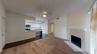 This well-appointed single-floor residence offers a thoughtfully designed open-concept layout that seamlessly connects the living and kitchen areas. The living room is anchored by a clean marble-surround fireplace and features plush carpeting, creating a warm and inviting atmosphere. A ceiling fan provides additional comfort throughout the space.

The kitchen is a standout feature, showcasing two-tone cabinetry with white upper cabinets and grey lower cabinets, granite countertops, a mosaic tile backsplash, and a large central island with additional seating space. Stainless steel appliances — including a range, microwave, and refrigerator — complement the modern aesthetic, while pendant lighting and track lighting illuminate the workspace. Wood-look flooring runs throughout the kitchen, adding warmth and durability.

The bedrooms are carpeted and generously sized, each featuring vertical blinds over large windows that allow for natural light and privacy. The primary bathroom offers a dual-sink vanity with granite countertops and grey cabinetry, consistent with the design language found throughout the home. A dedicated laundry area with washer and dryer hookups is conveniently accessible from the bathroom. The overall color palette of soft whites and greys lends the space a clean, contemporary feel.