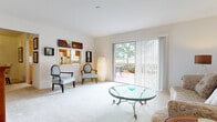 Located at 8570 Jamestown Dr in Winter Haven, Florida, this single-story home offers a thoughtfully designed layout with a clean, neutral aesthetic throughout. The spacious living room is highlighted by plush carpeting and large sliding glass doors that flood the space with natural light and open directly onto a private outdoor patio, providing seamless indoor-outdoor living. A dedicated dining area features an intimate setting with a ceiling light fixture and tasteful wall décor, ideal for sit-down meals. The kitchen is equipped with warm wood cabinetry, a double-basin sink, a dishwasher, a full-size refrigerator, and a window that brings in additional natural light. The bedroom is generously sized with soft carpeting, a broad window, and ample space for full bedroom furnishings. Two bathrooms serve the home — one features a wide vanity with a large mirror, white cabinetry, and a separate shower area, while the second includes a full tub-shower combo, wood-look flooring, and white fixtures. Throughout the home, soft neutral tones, carpeted living spaces, and consistent finishes create a cohesive and comfortable atmosphere suited for everyday Florida living.