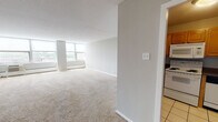 Located at 1501 Maple Ave in Evanston, Illinois, this single-floor unit offers a clean, functional layout designed for comfortable everyday living. The spacious living area is bathed in natural light through large windows that frame tree-lined outdoor views, and features neutral-toned carpeting and light gray walls that create a calm, airy atmosphere. Baseboard heating and a wall-mounted AC unit ensure year-round climate comfort.

The kitchen is well-equipped with warm wood cabinetry offering generous storage, dark laminate countertops, white appliances including an electric range, over-the-range microwave, and dishwasher, all set on easy-to-clean tile flooring.

The bedrooms are generously sized with plush carpeting and feature wide double closets with built-in hanging rods and shelving, providing ample storage. Each bedroom benefits from natural light and a neutral color palette that lends itself to a variety of furnishing styles.

The bathroom is neatly appointed with white cabinetry, a single-basin vanity, a mirrored medicine cabinet with Hollywood-style lighting, and a tub-shower combination, all finished with tile flooring for a clean, classic look. The overall layout is efficient and well-organized, making this a practical and comfortable Evanston residence.