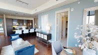 This sophisticated Dallas residence delivers an elevated urban living experience through thoughtful design and premium finishes. The open-concept living and dining area is anchored by dramatic floor-to-ceiling windows on two sides, flooding the space with natural light and framing breathtaking panoramic views of the Dallas skyline and surrounding greenery. Rich hardwood flooring flows throughout the main living areas, complementing the contemporary aesthetic.

The gourmet kitchen is outfitted with dark espresso cabinetry, granite countertops, stainless steel appliances, a gas range, and a breakfast bar with pendant lighting — ideal for both everyday cooking and entertaining. The adjoining dining nook, bathed in natural light from oversized windows, offers a refined setting with continued city views.

The primary bedroom is a serene retreat featuring a bold teal accent wall, large windows with skyline views, and plush carpeting. Its en-suite bathroom impresses with a dual-sink vanity, soaking tub, and a glass-enclosed walk-in shower finished in neutral tile. A secondary bedroom provides a cozy, well-appointed space with a ceiling fan and access to a second full bathroom featuring a clean white vanity. Soft blue accent walls and modern track lighting complete the refined, cohesive palette throughout this urban Dallas residence.