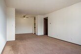 This single-floor residential unit offers a practical and comfortable layout designed to maximize everyday functionality. The living area is carpeted in a warm neutral tone and features a ceiling fan with integrated lighting, providing both comfort and airflow. Natural light filters in through vertical-blind-covered windows, brightening the space and creating an inviting atmosphere. Baseboard heating runs along the perimeter of the carpeted rooms, ensuring consistent warmth throughout.

The kitchen is efficiently appointed with cream-colored cabinetry featuring dark trim, dark laminate countertops, and a double stainless steel sink. Tile flooring and under-cabinet lighting add practical touches to the cooking space.

The bathroom is well-equipped with a wooden vanity cabinet topped by a white countertop and mirror, mosaic tile flooring, and a full tub-shower combination enclosed by floor-to-ceiling beige square tiles.

Storage is a notable feature of this unit, with a large built-in closet offering hanging rods and multiple shelving units, providing ample organization space. The overall layout, as seen in the dollhouse view, includes multiple rooms connected by a clear and logical flow, making this a well-structured and livable space.