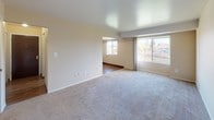 The Almond is a thoughtfully laid-out one-bedroom, one-bathroom residence spread across a single floor. The living area is generously proportioned, featuring neutral-toned walls, plush wall-to-wall carpeting, and large windows that invite abundant natural light while framing pleasant outdoor views of surrounding trees and water. A defined transition leads into a separate dining or flex area with wood-look flooring, providing a seamless connection to the kitchen.

The galley-style kitchen is well-equipped, featuring warm honey-toned wood cabinetry offering ample upper and lower storage, light countertops, a double-basin sink, and white gas appliances including a range and refrigerator. Wood-look flooring extends throughout this area, adding warmth and easy maintenance.

The bedroom is a comfortable retreat with soft carpeting, neutral walls, and a built-in closet with shelving for organized storage. An additional storage closet with built-in shelving is also accessible from the living area, adding practical utility to the floor plan.

The bathroom is clean and functional, featuring a full tub and shower combination with white tile surround, mosaic tile flooring, a vanity with sink, and chrome fixtures that lend a crisp, polished finish to the space.