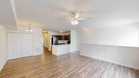 Located at 2411 Tinas Way in Seaford, Delaware, this well-appointed 2-bedroom, 2-bathroom single-story home offers a thoughtfully designed open-concept layout. The combined living and kitchen area forms the heart of the home, featuring durable wood-look flooring and a ceiling fan with integrated lighting. Large windows dressed with horizontal blinds invite abundant natural light, creating a bright and welcoming atmosphere throughout.

The kitchen is a standout feature, equipped with stainless steel appliances including a refrigerator, range, and over-the-range microwave. Rich, dark-toned cabinetry contrasts beautifully with light countertops and a peninsula that provides additional prep space and casual seating. A stainless steel undermount sink adds a clean, functional touch.

Both bedrooms are carpeted for comfort and include ceiling fans and closets. The spacious primary bedroom offers generous room for furnishings. A secondary bedroom features windows that bring in natural light. Both bathrooms are finished with wood-look tile flooring, dark vanity cabinetry, and full tub-shower combinations with clean white surrounds. The overall aesthetic of the home is clean, neutral, and move-in ready.