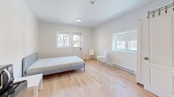 Located at 820 Rue Roy E in Montréal's vibrant Plateau-Mont-Royal neighborhood, this efficiently designed one-bedroom, one-bathroom unit makes excellent use of its compact footprint. The open-concept layout seamlessly integrates the kitchen and living/sleeping areas, creating a functional and cohesive living space.

The kitchen is well-appointed with white flat-panel cabinetry featuring sleek black hardware, a warm butcher block countertop, a stainless steel double sink, and a black ceramic cooktop with oven. Classic white subway tile forms the backsplash, adding a clean, timeless look. A striking exposed brick wall near the entry provides a bold architectural contrast to the otherwise bright, minimalist aesthetic.

The bedroom area is generously proportioned for the overall unit size, benefiting from multiple windows that invite abundant natural light and offer views of the surrounding greenery. Light-toned hardwood flooring runs throughout, enhancing the sense of openness and warmth.

The bathroom is finished in white large-format wall tiles and includes a full bathtub with shower and curtain, a pedestal sink, and recessed ceiling lighting.

Overall, the unit presents a clean, modern interior with thoughtful details — from the warm wood tones and white palette to the characterful brick accent — making it a practical and attractive space in one of Montréal's most sought-after neighborhoods.