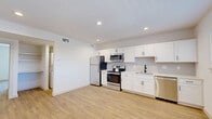 This thoughtfully designed single-story residence offers a clean, modern aesthetic across a comfortable, efficiently laid-out floor plan. The open-concept kitchen and living area serves as the heart of the unit, featuring crisp white shaker-style cabinetry, light-toned countertops, and a full suite of stainless steel appliances — including a refrigerator, electric range, over-the-range microwave, and dishwasher. Recessed lighting illuminates the space overhead, while light hardwood-style flooring runs seamlessly throughout, enhancing the bright and airy atmosphere. A window in the kitchen area invites natural light and provides a view of the surrounding neighborhood. The bedroom is a generously sized retreat, offering a ceiling fan, a wide closet with sliding doors, and a large window dressed with horizontal blinds for natural light and privacy. The layout also includes a dedicated hallway, a closet for additional storage, and an in-unit laundry area — a practical amenity that adds everyday convenience. The bathroom completes the unit. Throughout, the white walls and consistent flooring create a cohesive, neutral palette well-suited for a variety of furnishing styles. This unit combines functional design with modern finishes for comfortable everyday living.