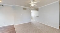 Located in San Marcos, Texas, this two-bedroom, one-bathroom residence offers a well-organized single-floor layout that makes efficient use of its space. The combined kitchen and living area forms the heart of the home, where wood-style flooring, crown molding, and a ceiling fan with light create a comfortable, functional atmosphere. The kitchen features white cabinetry, dark countertops, a double-basin sink, and black appliances including a refrigerator and range, with a breakfast bar peninsula that opens toward the living area. Natural light filters in through multiple windows fitted with blinds throughout the home. The spacious primary bedroom is carpeted and includes a ceiling fan, a double-door closet, and access to an adjoining walk-in closet equipped with wire shelving and a freestanding shelf unit for organized storage. The second bedroom is also carpeted and benefits from an arched window and its own ceiling fan, adding to the room's brightness and comfort. The bathroom is finished with a full tub-shower combination featuring white tile surround and chrome fixtures. Transitions between carpet and wood-style flooring delineate the living spaces, contributing to a clean, cohesive interior aesthetic throughout.
