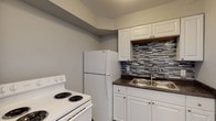This single-floor unit located on W Rich Street in Columbus, Ohio presents a clean, updated interior with a consistent neutral gray and white color palette throughout. Wood-look plank flooring runs through the living areas and bedroom, providing a cohesive and low-maintenance surface underfoot.

The kitchen is a functional highlight of the space, featuring white shaker-style cabinetry both above and below the counter, dark laminate countertops, and a stainless steel double-basin sink. A striking geometric mosaic tile backsplash in shades of gray adds visual interest. White Whirlpool appliances, including a coil-burner range and full-size refrigerator, are included.

The living area is open and versatile, with light-toned walls and access to adjoining rooms. A ceiling fan is installed in the bedroom, which also benefits from a window with horizontal blinds allowing natural light. The bathroom is straightforward and well-maintained, offering a full tub and shower combination with a white surround, updated fixtures, and wood-look flooring. The overall layout is practical and efficiently organized across a single level.