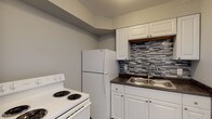 This single-floor unit located on W Rich Street in Columbus, Ohio presents a clean, updated interior with a consistent neutral gray and white color palette throughout. Wood-look plank flooring runs through the living areas and bedroom, providing a cohesive and low-maintenance surface underfoot.

The kitchen is a functional highlight of the space, featuring white shaker-style cabinetry both above and below the counter, dark laminate countertops, and a stainless steel double-basin sink. A striking geometric mosaic tile backsplash in shades of gray adds visual interest. White Whirlpool appliances, including a coil-burner range and full-size refrigerator, are included.

The living area is open and versatile, with light-toned walls and access to adjoining rooms. A ceiling fan is installed in the bedroom, which also benefits from a window with horizontal blinds allowing natural light. The bathroom is straightforward and well-maintained, offering a full tub and shower combination with a white surround, updated fixtures, and wood-look flooring. The overall layout is practical and efficiently organized across a single level.