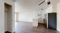 This single-floor, 1-bedroom, 1-bathroom residence offers a thoughtfully designed layout that maximizes functionality and comfort. The open-concept kitchen and living area serves as the heart of the home, featuring durable wood-look plank flooring throughout and a textured ceiling with a ceiling fan overhead. The kitchen is outfitted with crisp white cabinetry, a peninsula with a light countertop that doubles as a breakfast bar, stainless steel appliances including a refrigerator and range, and a built-in sink — all combining practicality with a clean aesthetic. The living room flows seamlessly from the kitchen and is filled with natural light from a sliding glass door that opens to a private balcony with outdoor views. The bedroom is a comfortable, carpeted retreat featuring a triple-panel sliding closet for generous storage and a window with blinds that allow natural light while maintaining privacy. The full bathroom includes a tub-shower combo with tile surround, a toilet, and wood-look flooring that ties into the rest of the home. Throughout, neutral warm tones and simple finishes create a bright, move-in-ready atmosphere.