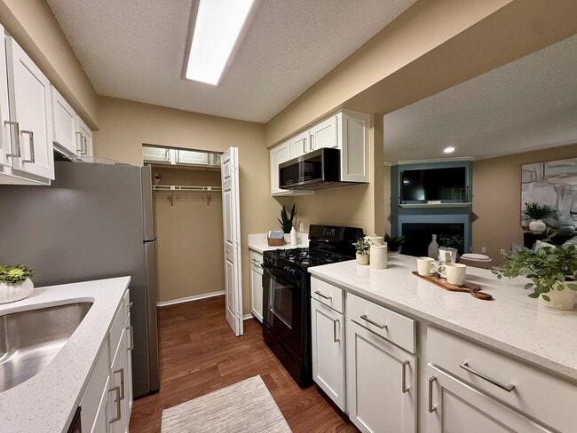 Kitchen with granite counters, modern cabinetry, and black appliances - Vetra at Hamilton Place