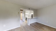 Located at 1250 Woodcrest Dr in Daytona Beach, FL, this one-bedroom, one-bathroom unit offers a well-designed single-floor layout with a clean, modern aesthetic. Light-toned wood-look flooring runs throughout, complementing the neutral gray walls and white trim for a cohesive, contemporary feel.

The open living area is bright and welcoming, featuring a textured ceiling, a shiplap-accented accent wall, and a sliding glass door that fills the space with natural light and provides access to a private balcony. The kitchen is connected via a peninsula with a granite countertop overhang, ideal for casual dining. White shaker-style cabinetry, subway tile backsplash, stainless steel appliances — including a refrigerator and range — and a skylight-style overhead fixture complete the kitchen's polished look.

The bedroom is a comfortable size, offering two doorways — one leading to a closet and one to the hallway — along with a window that brings in additional natural light. The bathroom features a wide granite-topped vanity with white shaker cabinetry, a large framed mirror, and a tub-shower combination, delivering both style and function.

This efficiently designed unit makes excellent use of its footprint, offering practical living spaces with quality finishes throughout.