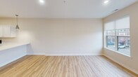 Located at 900 Third St SE in Cedar Rapids, Iowa, this 2-bedroom, 2-bathroom unit offers a thoughtfully designed single-floor layout with generous living space. The open-concept kitchen and living area serves as the heart of the home, featuring light hardwood-style flooring, recessed lighting, and large windows that invite natural light and urban views of the surrounding neighborhood. The kitchen is equipped with white shaker-style cabinetry, white quartz countertops, stainless steel appliances including a French door refrigerator, electric range, and built-in microwave, complemented by a pendant light fixture.

The living room benefits from a row of large windows with roller shades, offering views of the streetscape. Both bedrooms are carpeted and feature ceiling fans, generous closet space with built-in shelving, and windows providing natural light. The spacious primary bedroom includes its own en-suite bathroom with a white vanity, quartz countertop, walk-in shower, and access to a walk-in closet with wire shelving. The second bathroom mirrors the same clean, modern aesthetic. A dedicated laundry room houses a full-size washer and dryer with overhead wire shelving, adding everyday convenience to this well-finished urban residence.
