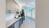 Located in Redmond, WA, this single-floor residence offers a thoughtfully designed layout with modern finishes throughout. The galley-style kitchen is a standout feature, showcasing two-tone cabinetry with light wood upper cabinets and slate-gray lower cabinets, accented by matte black hardware. Quartz countertops, a geometric tile backsplash, and stainless steel appliances — including a refrigerator, electric range, over-the-range microwave, and dishwasher — complete the contemporary look. Light wood-style flooring runs through the kitchen and flows seamlessly into the open living area, which is bathed in natural light from a bank of large windows fitted with horizontal blinds. The bedrooms feature plush carpeting and ceiling fans, providing a comfortable retreat. One bedroom includes a closet with built-in shelving. The bathrooms are finished with large-format tile flooring and white subway tile surrounds in the tub/shower combination, maintaining the clean, neutral aesthetic found throughout the home. Ceiling fans in the main living spaces and bedrooms add practical comfort, while the bright, white walls and light palette create an airy, welcoming ambiance throughout this well-appointed Redmond residence.