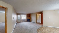 Located at 2321 Troop Dr in Sartell, MN, this single-floor unit offers a well-organized layout with a comfortable, functional design throughout. The spacious living room is finished with plush carpeting and features a built-in fireplace flanked by wood cabinetry, a window that invites natural light, and baseboard heating. An arched passthrough connects the living area to the galley-style kitchen, which is equipped with warm oak cabinetry, ample counter space, a double-basin sink, and white appliances including a range and refrigerator. Tile flooring runs through the kitchen and entry areas, providing a durable contrast to the soft carpet found in the living and bedroom spaces. A chandelier accents the dining area adjacent to the kitchen. The bedrooms are generously sized, each featuring carpet, baseboard heating, and windows for natural light. The primary bedroom includes a walk-in closet with built-in shelving. Two bathrooms serve the unit — one with a vanity, mirror, and tile flooring, and another with a full tub-shower combo and checkered tile flooring. Textured ceilings are consistent throughout, contributing to the unit's classic residential character.