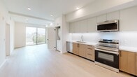 Located at 856 Gramercy Dr in Los Angeles, this thoughtfully designed one-bedroom, one-bathroom residence offers a clean, modern aesthetic throughout its single floor of living space. Light wood-tone flooring flows seamlessly across every room, complementing the bright white walls and recessed lighting that create a warm, airy atmosphere.

The open-concept living and kitchen area is a standout feature, anchored by a contemporary kitchen outfitted with stainless steel appliances — including a French door refrigerator, electric range with microwave, and dishwasher. Two-tone cabinetry pairs warm natural wood lower cabinets with matte gray upper cabinets, finished with a crisp white countertop and a textured tile backsplash. A large sliding glass door opens to a private balcony, flooding the living area with natural light and offering views of the surrounding neighborhood.

The spacious bedroom includes a dedicated walk-in closet and recessed lighting, offering a comfortable and functional retreat. A stacked in-unit washer and dryer adds everyday convenience. The bathroom features a floating wood vanity with a white countertop, a framed mirror, and a full bathtub with shower. A connecting hallway ties all rooms together efficiently, completing this well-appointed urban residence.