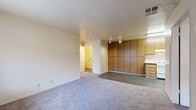 Located at Village Center Drive in Sacramento, CA, this 2-bedroom, 1-bathroom single-floor home offers a practical and comfortable layout. The open living area flows directly into the kitchen, creating a connected and functional space. The kitchen features warm oak-toned cabinetry, a full-size refrigerator, a dishwasher, a stove, and a stainless steel sink with light countertops, all set on wood-look vinyl flooring. A striking wall of floor-to-ceiling wood-panel cabinetry serves as a defining architectural feature between the living and kitchen areas, providing generous storage. The living area is finished with plush carpet and equipped with track lighting overhead. Both bedrooms are carpeted and bathed in natural light through large windows dressed with vertical blinds. The primary bedroom includes a dedicated closet area, while the second bedroom features sliding mirrored closet doors. The full bathroom is finished with wood-look vinyl flooring, a tub-shower combination with safety grab bars, and clean, neutral-toned walls. A utility room and additional closet space round out the home's practical offerings. The overall aesthetic is clean, neutral, and move-in ready.