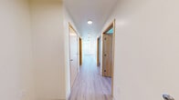 Located at The Rise in the heart of Seattle, WA, this thoughtfully designed 3-bedroom, 3-bathroom residence offers a clean, modern aesthetic across a single floor. Light wood-toned luxury vinyl flooring runs throughout the unit, creating a cohesive and warm feel from room to room.

The kitchen is a standout space, featuring light maple cabinetry, ample counter and storage space, white appliances, and an exposed concrete ceiling that adds an industrial character. Large windows flood the kitchen with natural light and frame sweeping views of the Seattle skyline.

A central hallway connects the three bedrooms and three bathrooms with ease. Each bedroom is bright and airy, offering city views through generously sized windows with warm wood sills. The primary bedroom includes a walk-in closet with built-in shelving. The bathrooms are finished with light maple vanities, wide mirrors, and tub/shower combinations equipped with grab bars, reflecting an accessibility-conscious design.

The exposed concrete ceilings in select areas and the clean white walls throughout give the space a contemporary urban character, while the abundance of natural light and panoramic city views from multiple rooms reinforce the elevated position of this residence within the Seattle skyline.